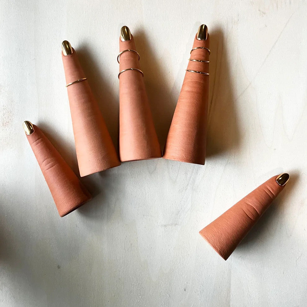 Each finger is made from terracotta clay and finished with a gold luster on the nail. Each finger can fit ring size 9 through 4.