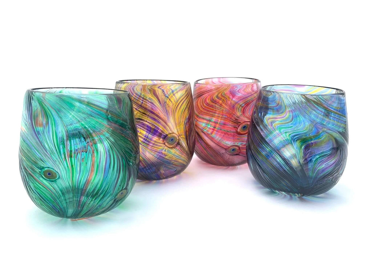 These handmade drinking glasses are crafted using traditional blown glass techniques and feature a mesmerizing peacock-inspired pattern.