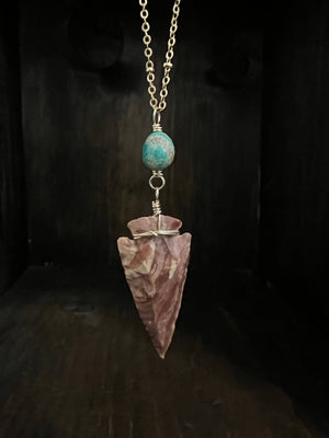 Reddish brown arrowhead with an Elisa Turquoise accent hanging on an 18” long brass satellite chain with a gold filled spring ring clasp.