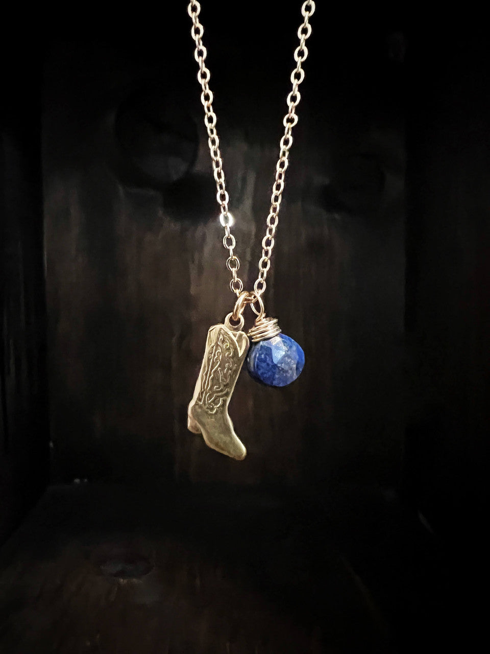 A .75” brass cowboy boot charm paired with a faceted lapis drop and hanging on an 18” dainty brass chain with a gold filled spring ring clasp.