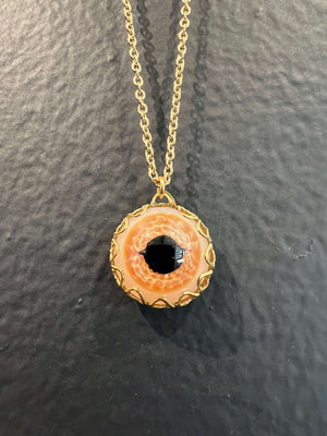 Handblown Orange borosilicate glass eye caged in vintage brass filigree and hanging on a brass chain.