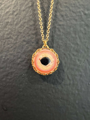 Hand blown Pink borosilicate glass eye caged in vintage brass filigree hanging on an 18" long brass chain.